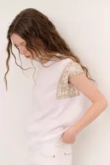 Blusa de lino color beige con cuello redondo y detalles de crochet en los hombros.
