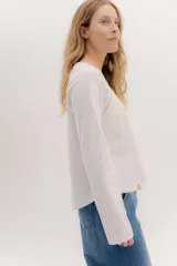 Remera blanca de manga larga con escote a la base. La parte delantera es de algodón y la espalda de remería para mayor elasticidad. Las mangas combinan ambas telas y presenta un detalle de doble entredos en la sisa delantera.