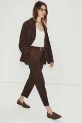 Pantalón de tiro alto en color beige, con diseño de pinzas frontales y bolsillos laterales. Incluye un cinturón a contraste en tono marrón con hebilla metálica y cierre frontal con cremallera y gancho.
