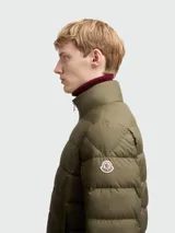 Chaqueta acolchada Moncler modelo Baudinet, color verde oliva, con cierre frontal completo, cuello alto y diseño de costuras horizontales. Incluye bolsillos laterales y logo de la marca en la manga.