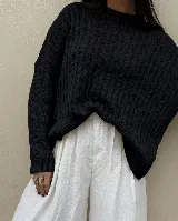 Sweater de punto color negro con diseño de trama de espiga en la parte frontal, cuello redondo y mangas largas con puños acanalados.