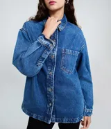 Camisa oversized de jean azul, con cuello padre, mangas largas con puños abotonados y cierre frontal con botones. Incluye un bolsillo aplicado en el pecho y bajo redondeado.