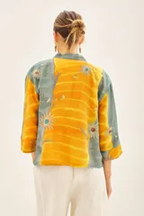 Kimono corto de viscosa con diseño estampado en tonos amarillo y gris, decorado con bordados en hilo de lurex. Presenta un corte holgado con mangas tres cuartos y un cinturón integrado de la misma tela.