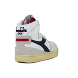 Zapatilla de caña alta Diadora Heritage modelo Mi Basket, color blanco con detalles en azul marino, beige y rojo. Presenta un acabado envejecido en la suela de goma. En la lengüeta se observa un gráfico en blanco y negro de una figura masculina.