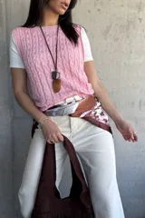 Chaleco tejido de punto color rosa con diseño de trenzas.