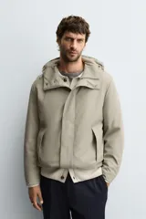 Parka de tejido técnico con acabado engomado, cuello subido y capucha ajustable. Presenta cierre frontal con cremallera oculta bajo solapa con botones a presión, bolsillos laterales de vivo y mangas largas con puños ajustables.