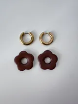 Aros de acero quirúrgico dorados con argollas pequeñas y dijes colgantes en forma de flor color celeste.
