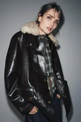 Chaqueta de efecto cuero color marrón oscuro con acabado brillante, cuello de solapa con aplicación de pelo sintético extraíble, manga larga con trabillas, bolsillos frontales de plastrón con solapa y cierre frontal con cremallera y botones a presión.