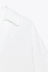 Camisa blanca de lino con cuello solapa, escote pico, manga ancha por debajo del codo con vuelta y bajo asimétrico.