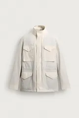 Cazadora relaxed fit de hombre color beige, confeccionada en tejido técnico acolchado. Cuenta con cuello subido, manga larga con puños ajustables, múltiples bolsillos frontales de plastrón con solapa, cintura ajustable con cordón interior y cierre frontal de cremallera oculta por solapa.