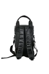 Mochila tipo bolso cilíndrico, acolchada y color negro, con asas superiores y correa ajustable para llevar al hombro. Presenta varios parches decorativos, incluyendo uno con coordenadas geográficas y otro con el texto "MAKE YOUR WORLD BIGGER".