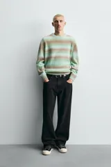 Jersey de punto con ajuste relajado, cuello redondo y manga larga. Presenta un diseño de rayas horizontales difuminadas en tonos verde agua y marrón, con acabados en rib en cuello, puños y ruedo.