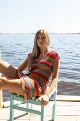 Vestido corto tejido a crochet con diseño de bloques de colores vibrantes, escote redondo y mangas cortas.