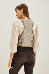 Chaleco corto con diseño de lentejuelas brillantes en tono dorado y plateado. Presenta un corte clásico con bordes definidos y forro interior suave.