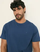 Remera básica de algodón color beige, de manga corta, con cuello redondo y un pequeño detalle bordado en el pecho.