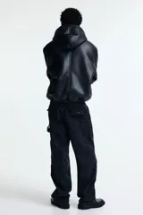 Pantalón estilo carpenter de corte holgado, confeccionado en tejido de algodón. Presenta tiro caído, bolsillos laterales de parche, trabilla funcional en una pierna y costuras reforzadas visibles sobre y debajo de las rodillas.