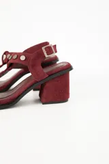 Sandalias de cuero color marrón con taco cuadrado, tiras con apliques metálicos y hebilla de ajuste en el tobillo.