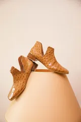 Botin de cuero con acabado grabado efecto avestruz, diseño con aberturas laterales y taco bajo cuadrado.