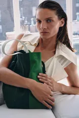 Bolso de hombro maxi en piel con diseño bicolor en tonos verde oscuro y verde brillante, con cierre fruncido y asa de hombro en color blanco.