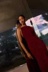 Vestido largo bordó con brillos, escote halter y diseño fluido de corte acampanado.