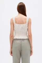 Musculosa de viscosa color negro con estampado de lunares blancos, tirantes anchos con volados fruncidos, escote cuadrado con cordones ajustables en el centro y cuerpo elástico con punto smock.