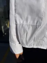 Camisa blanca de tejido texturado, corte oversize con mangas largas y puños anchos.
