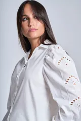 Camisa blanca de mangas largas con broderie y botones perlados.