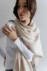 Bufanda de tejido suave en color beige, con diseño liso y terminaciones clásicas.
