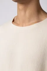 Remera de corte oversize confeccionada en tejido texturado tipo lino, de color beige, con cuello redondo amplio y mangas cortas de calce relajado.