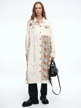 Chaqueta larga tipo camisa con diseño patchwork, confeccionada mediante la combinación de diversas texturas y estampados florales en tonos crudos, beige y naranja. Presenta cuello clásico, cierre frontal con botones y mangas largas.
