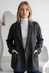 Tapado de paño color marrón, de corte oversize, con solapas clásicas, cierre frontal de doble botonadura y bolsillos laterales de parche.