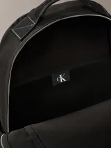 Mochila negra de poliéster reciclado con asa de mano y correas ajustables acolchadas. Tiene cierre principal con cremallera, bolsillo frontal con cremallera, bolsillos laterales expandibles y funda interior acolchada para portátil.