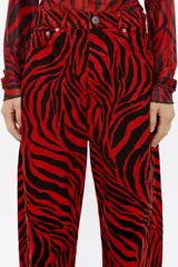 Pantalón vaquero de corte barrel, tiro medio, largo tobillero y estampado animal print de cebra en rojo y negro.