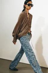 Pantalón jean tiro alto de corte flare con diseño jacquard estampado completo, cinco bolsillos, trabillas para cinto y cierre frontal con cremallera y botón metálico.