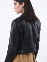 Chaqueta de cuero negra estilo motociclista con cierre cruzado, cuello con solapas y múltiples bolsillos con cremallera.