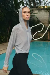 Sudadera de punto con hilo metalizado color gris, con capucha, manga larga y cierre frontal con cremallera.