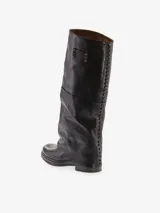 Bota alta de cuero vacuno color marrón oscuro con diseño de polaina integrada. Presenta detalles de tachas metálicas a lo largo de la costura posterior y una placa metálica decorativa en la parte superior de la caña. Posee taco bajo y punta redondeada.