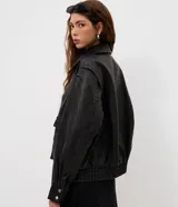 Campera de estilo urbano con corte oversized, confeccionada en poliuretano con base de poliéster. Presenta cuello clásico, cierre frontal con botones a presión, mangas largas y dos bolsillos frontales con tapa. El bajo cuenta con elástico para un mejor ajuste.