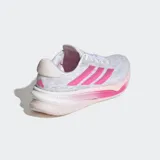 Championes de running Adidas modelo Comfortglide para mujer, con parte superior de malla transpirable en color blanco y gris. Destacan las tres tiras laterales en color fucsia y una entresuela Dreamstrike diseñada para brindar amortiguación y confort. Cuentan con cierre de cordones y detalles reflectantes.