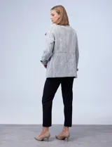 Tapado corto de lana y poliéster, con tejido tweed en tonos blanco y negro. Presenta cuello con solapa, doble abotonadura frontal en color negro y bolsillos verticales.