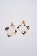 Aros colgantes con diseño floral, compuestos por pétalos metálicos dorados y una flor central de tela blanca semitransparente.