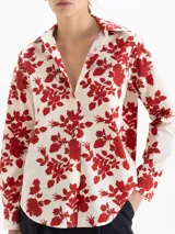 Camisa de poplin de algodón con estampado floral y de fresas en color rojo sobre base crema. Presenta cuello camisero, cierre frontal con botones y mangas largas con puños abotonados.