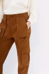 Pantalon cargo negro de calce relajado con ajuste en los tobillos. Cuenta con bolsillos laterales con solapa y cintura con cierre, botón y elástico en la parte posterior.