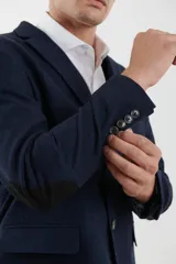 Saco azul oscuro de corte clásico, con solapa de muesca, cierre de dos botones, tres bolsillos delanteros y puños con cuatro botones.