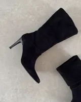 Botas de caña media confeccionadas en cuero vacuno negro, con diseño de punta fina y taco aguja alto.