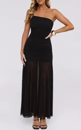 Vestido largo negro de un solo hombro con tirante delgado, diseño ajustado con fruncidos en el cuerpo y parte inferior translúcida de gasa.