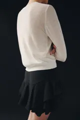 Shorts de tiro medio confeccionado en mezcla de viscosa, con diseño de volantes en el bajo y cierre lateral con cremallera oculta.