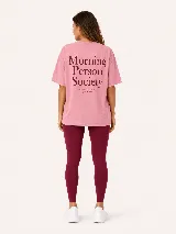 Remera oversize color tostado, con mangas cortas y cuello redondo. Presenta un gran estampado en la espalda con la inscripción "Morning Person Society" y un texto secundario en tipografía más pequeña.