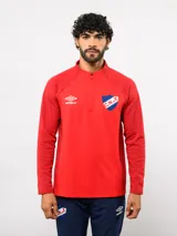 Buzo de entrenamiento Umbro del Club Nacional de Football, con medio cierre frontal, cuello alto y mangas largas. Presenta el logo de la marca y el escudo del club en el pecho.