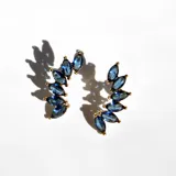 Par de aros trepadores dorados con cristales azules en forma de lágrima.
